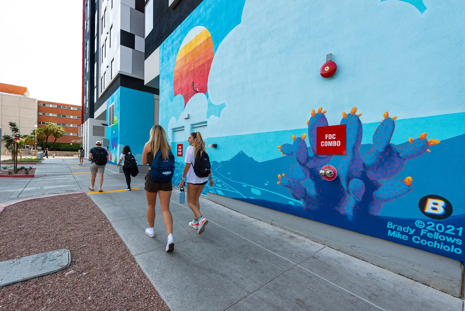 students walking next to a mural